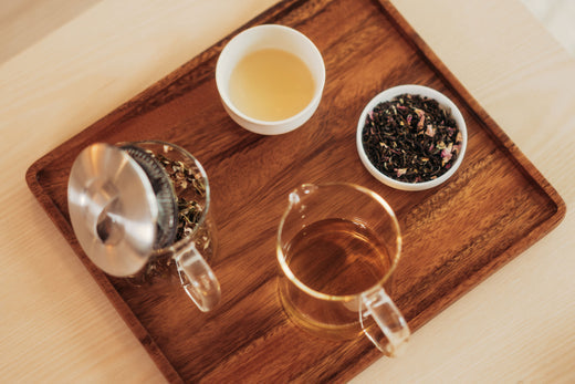 Aufgebrühter Schwarztee und Teeblätter auf Holztablett