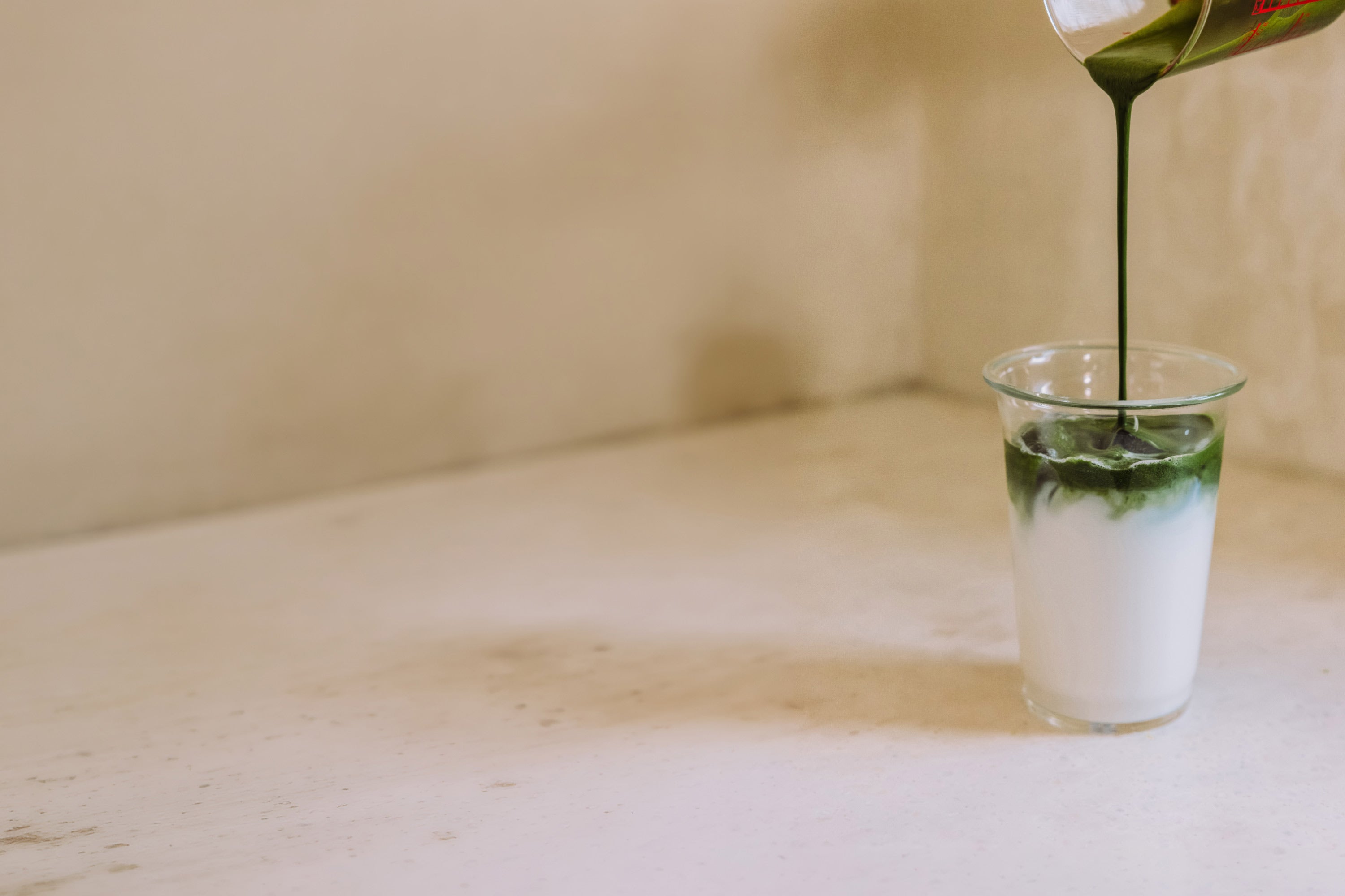 Grüner Hintergrund mit dunkelgrünen Blattformen an den Seiten und kleinem Kreisbild rechts, das eine Person mit grünem Becher und Matcha-Getränk zeigt