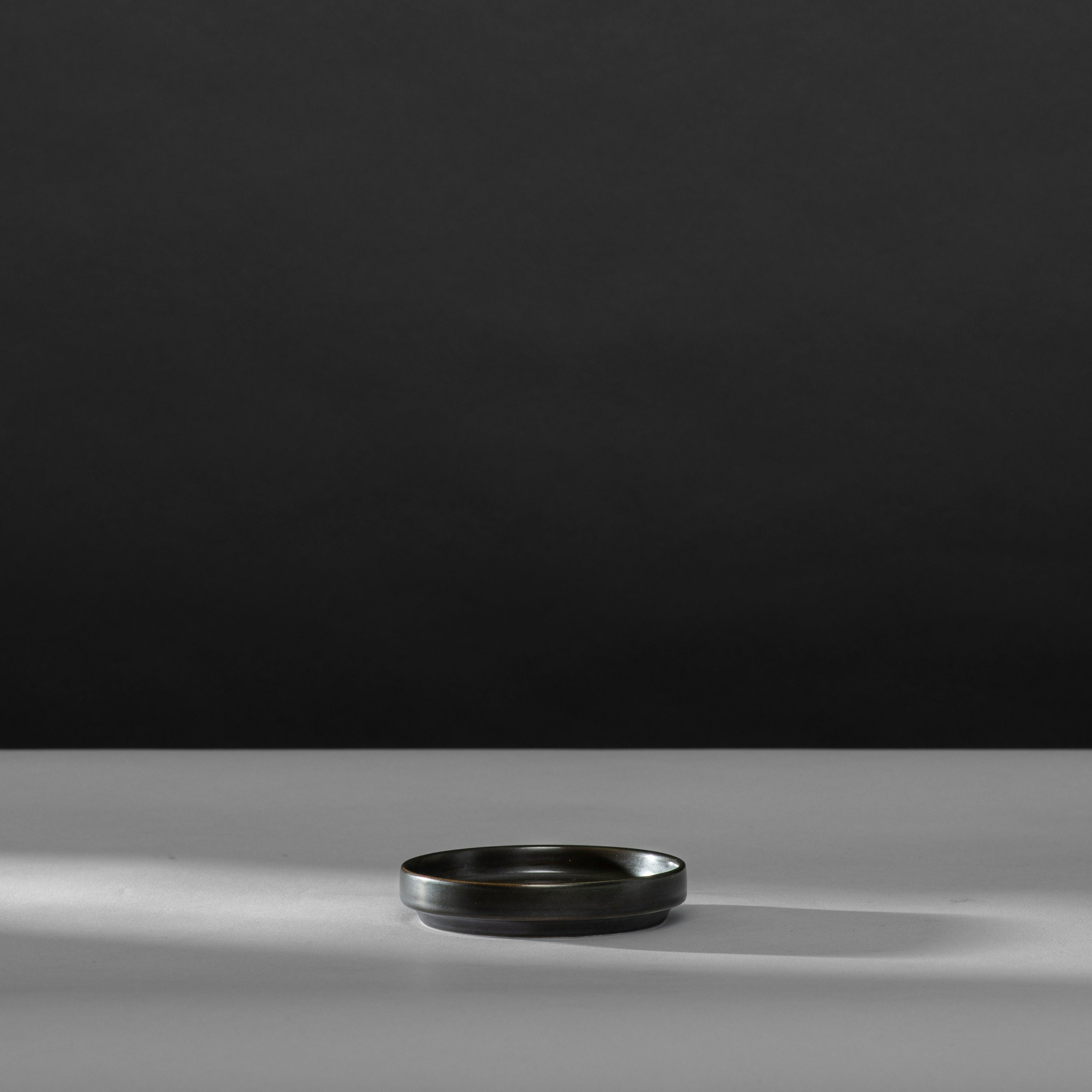 Schwarzes, rundes Tablett auf hellgrauer Oberfläche, minimalistisch und elegant.