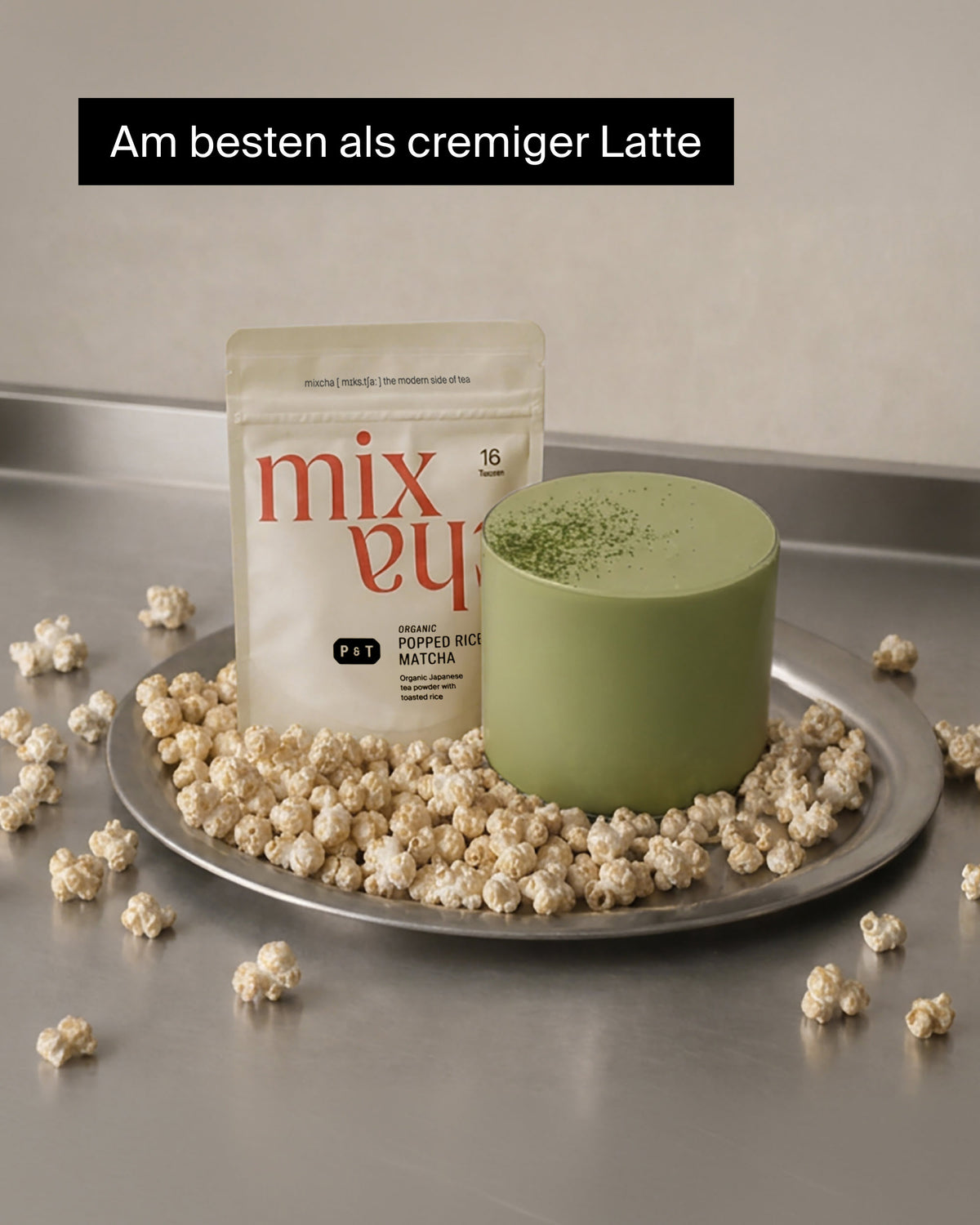 Beige Packung mit Bio-P&T Popped Rice Matcha neben mintgrünem Matcha Latte auf Metalltablett mit geröstetem Reis