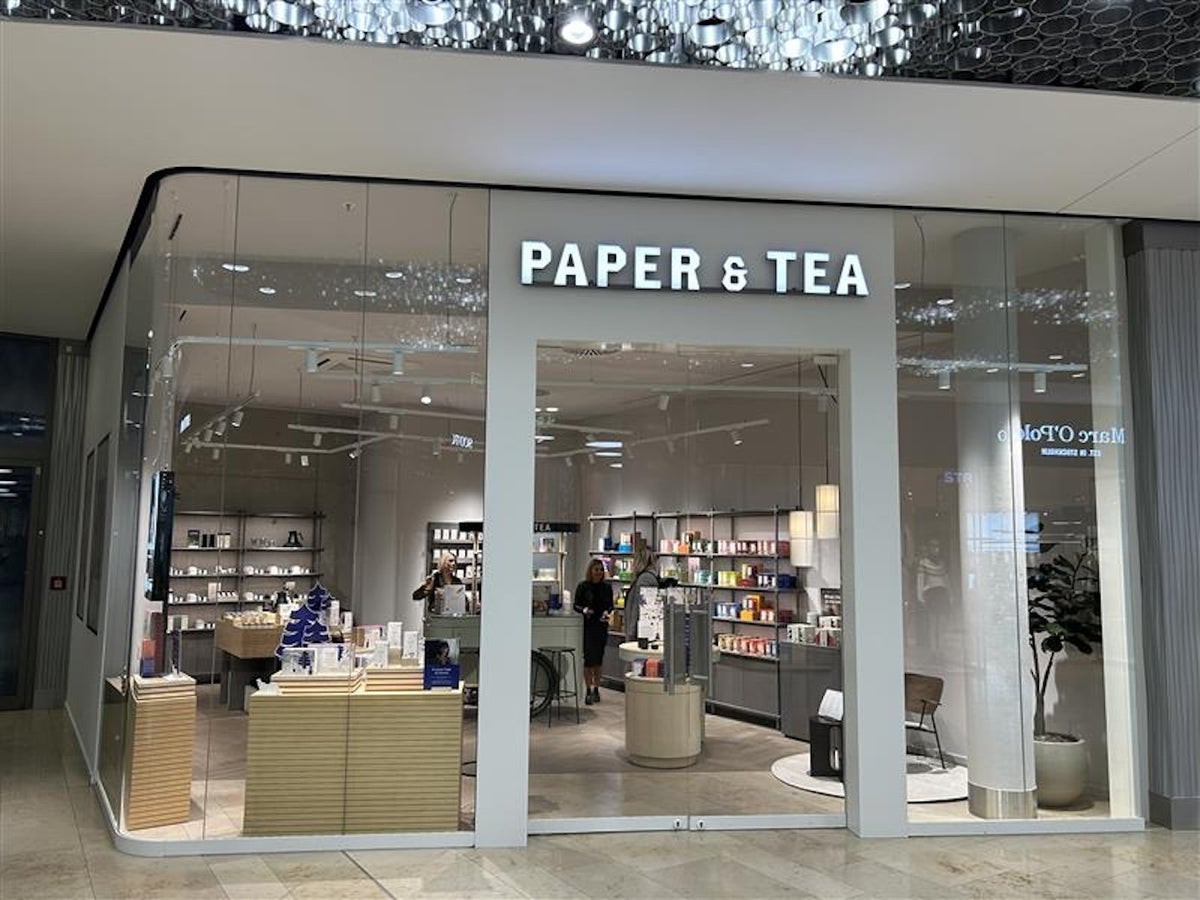 Eingang zum PAPER & TEA Laden mit festlichen Tischen und bunten Produktregalen.