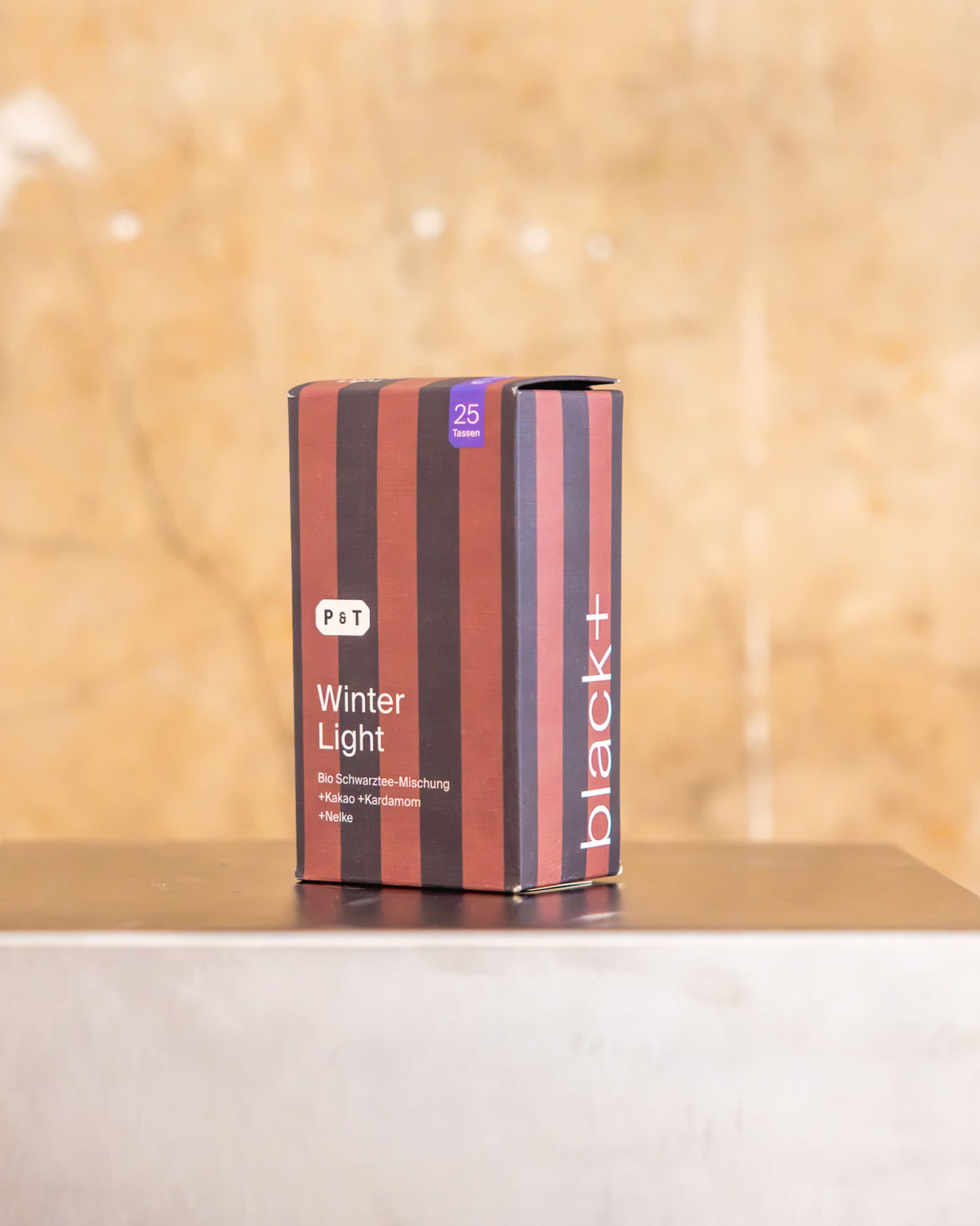 Schwarzer Tee Winter Light von P&T mit Bio-Schwarzmischung, Kakao, Kardamom und Nelke in gestreifter Verpackung.
