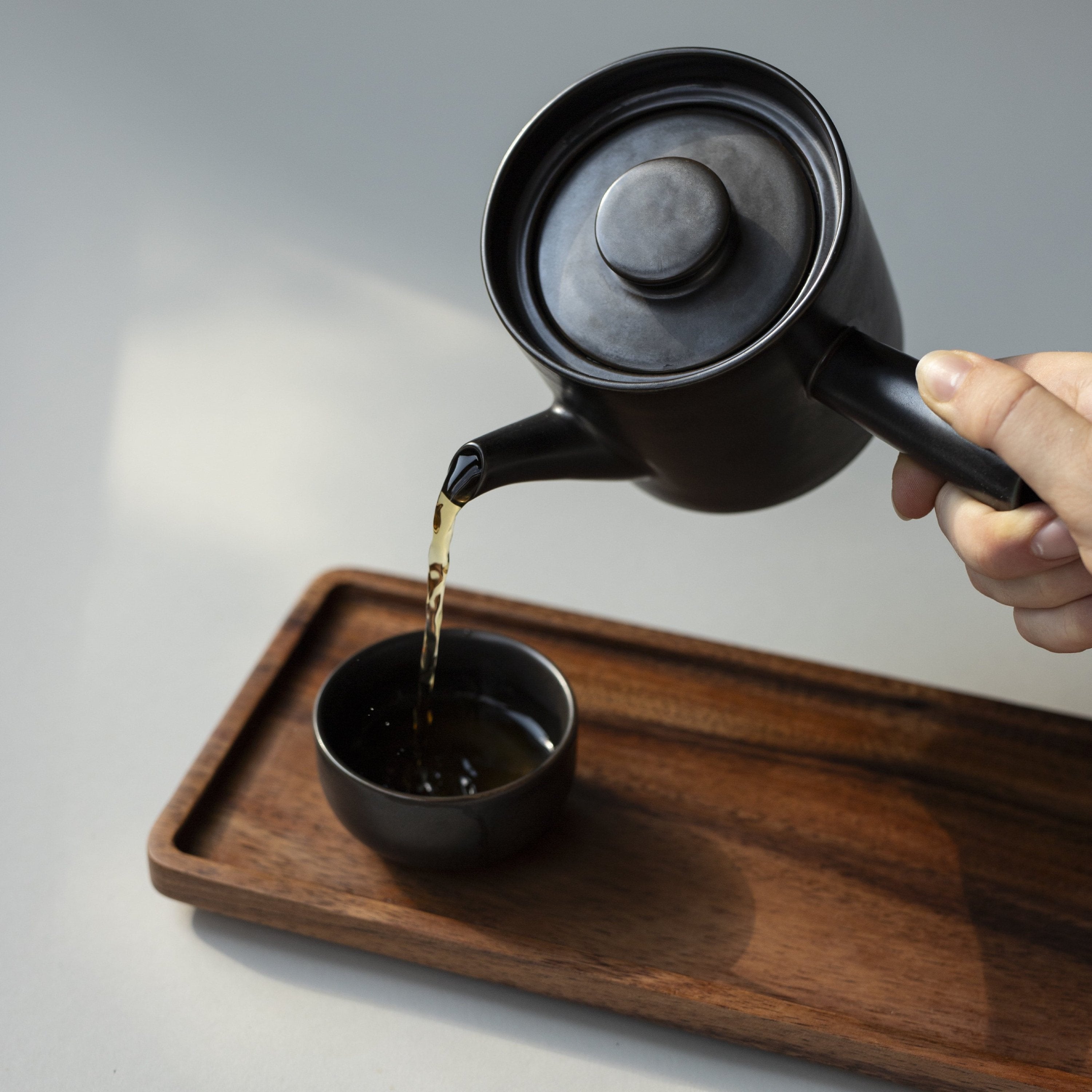 Schwarzer Kyusu und Tasse auf Holz-Tablett