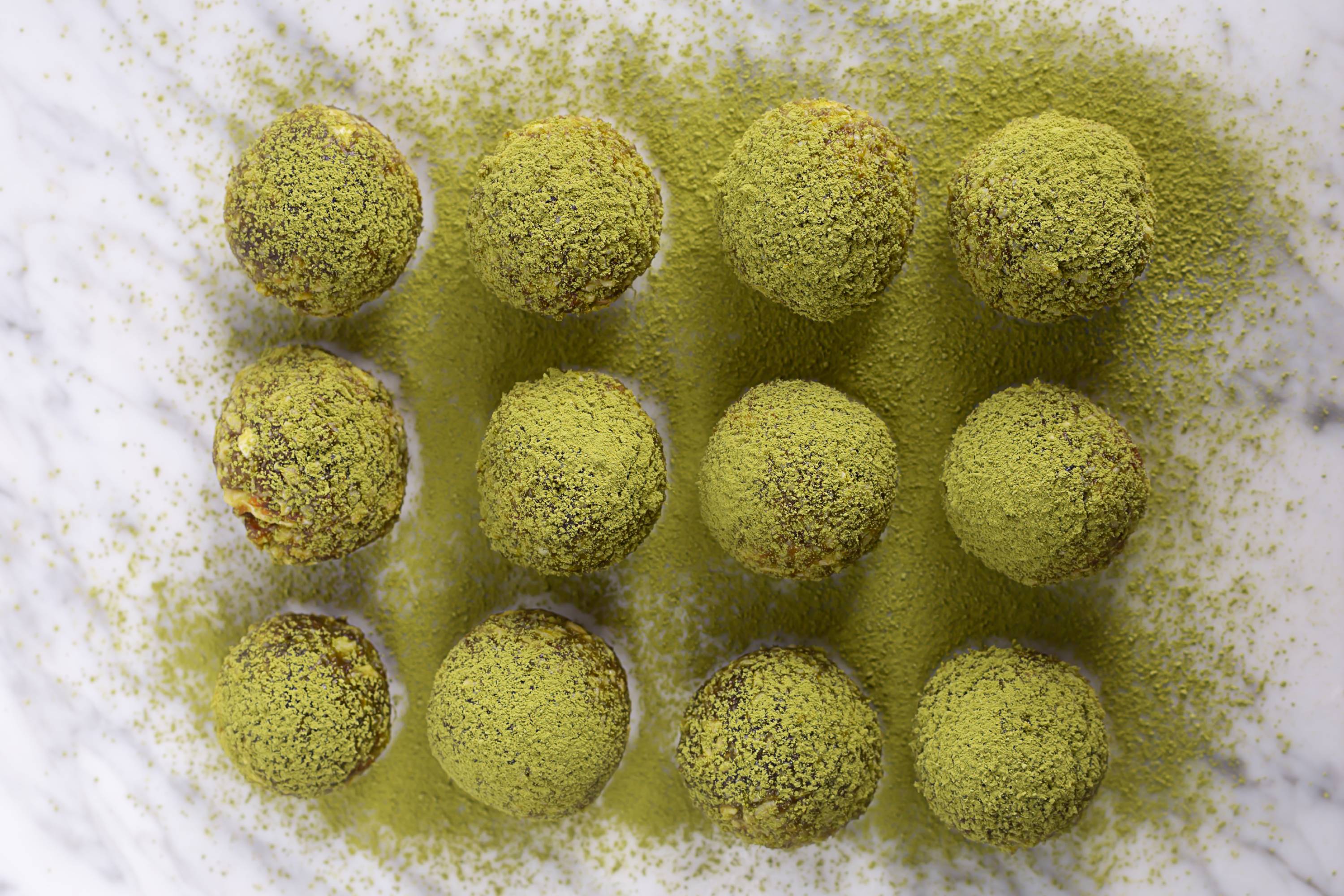 Energy Balls mit grünem Matchapulver bestäubt auf einer Küchenarbeitsfläche liegend