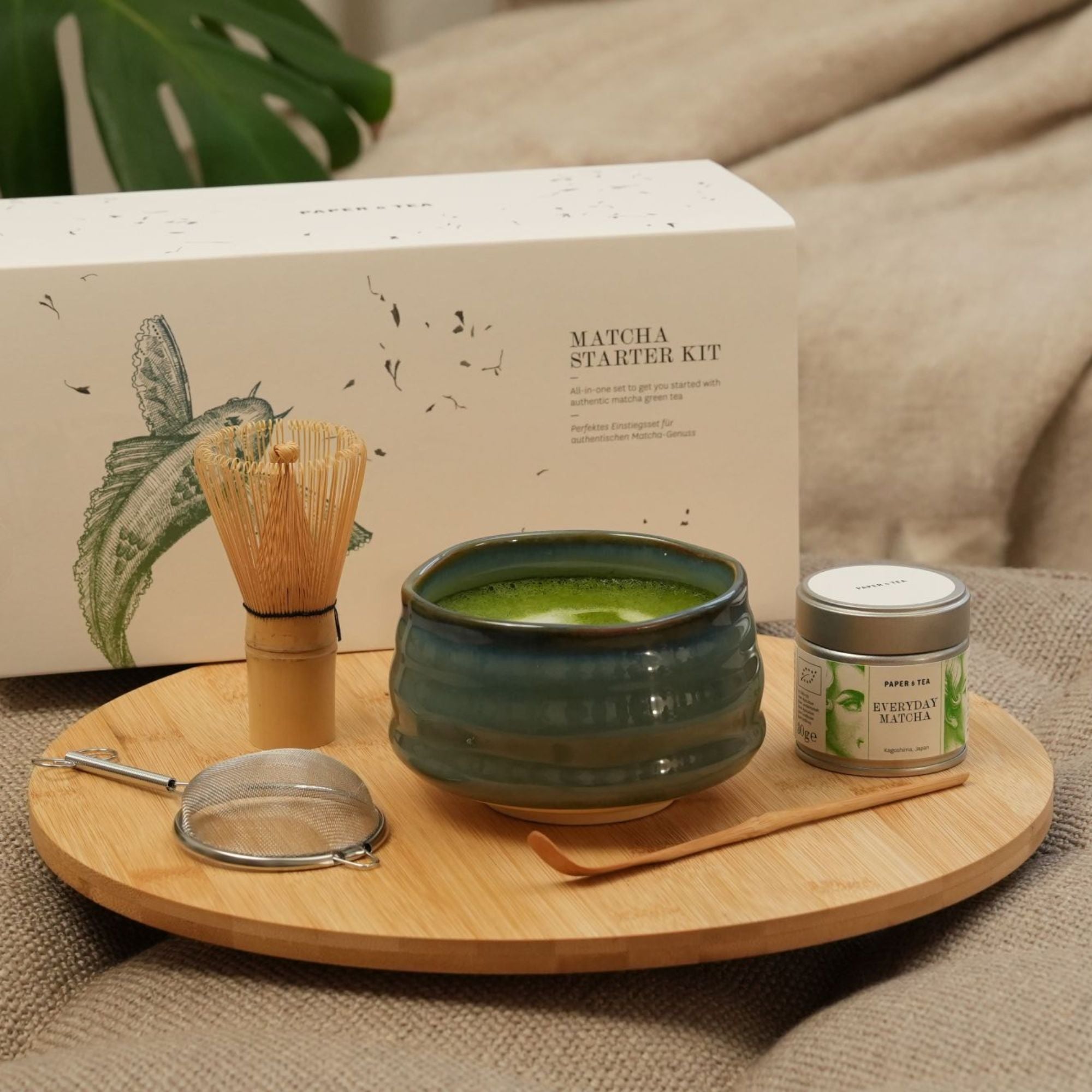 Matcha Starter Kit von Paper & Tea mit grünem Becher, Bambusbesen, Sieb und Matcha-Dose auf Tablett.