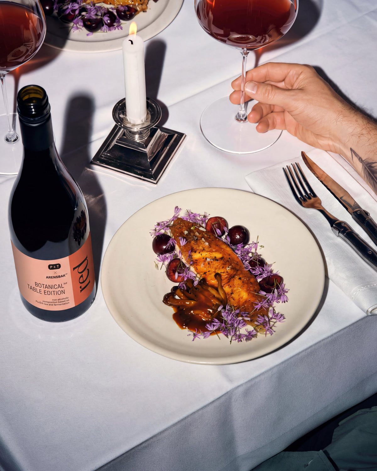 Elegantes Tischarrangement mit P&T Arensbak™ Botanical Flasche, Gourmetfisch, Wein und Kerze.