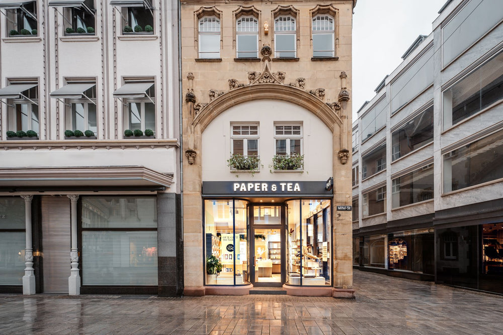 Charaktervolles P&T-Geschäft mit heller Beleuchtung und Sandsteinfassade in einer Kopfsteinpflasterstraße.