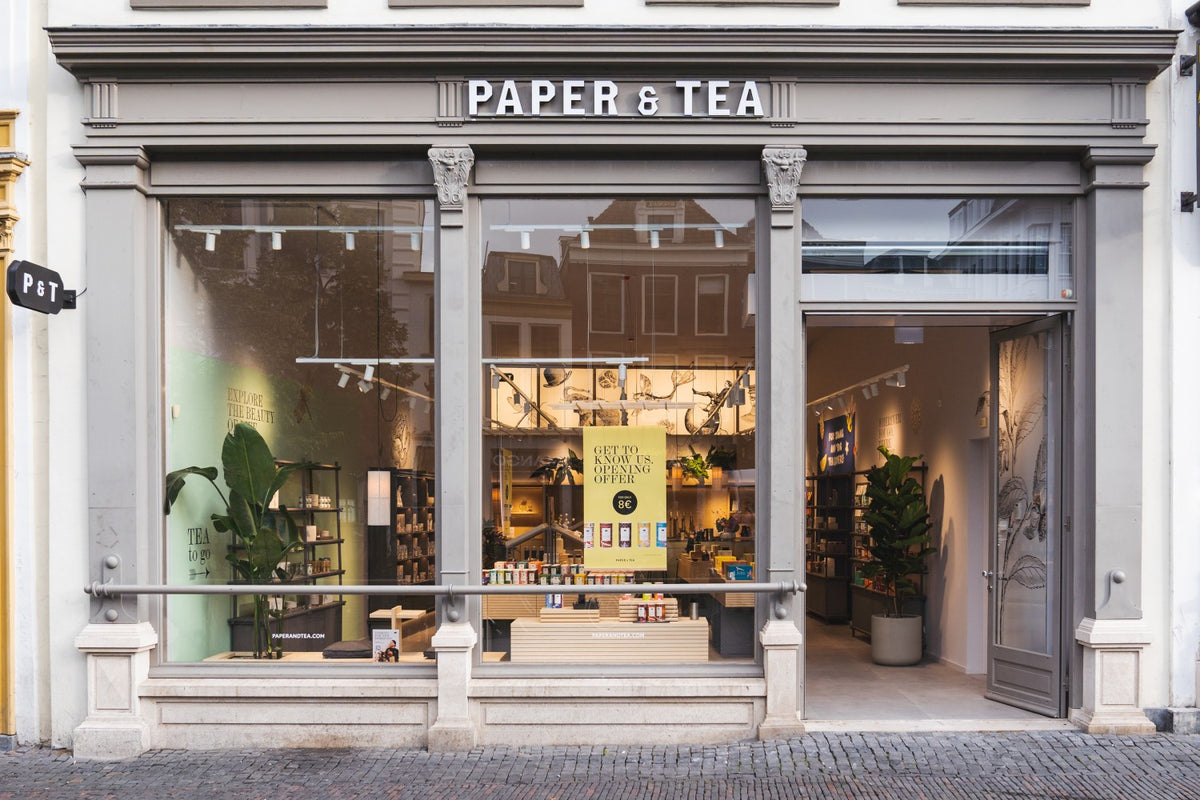 Elegante Ladenfront von PAPER & TEA mit großen Fenstern, offener Tür und Eröffnungsangebot für 8 €.