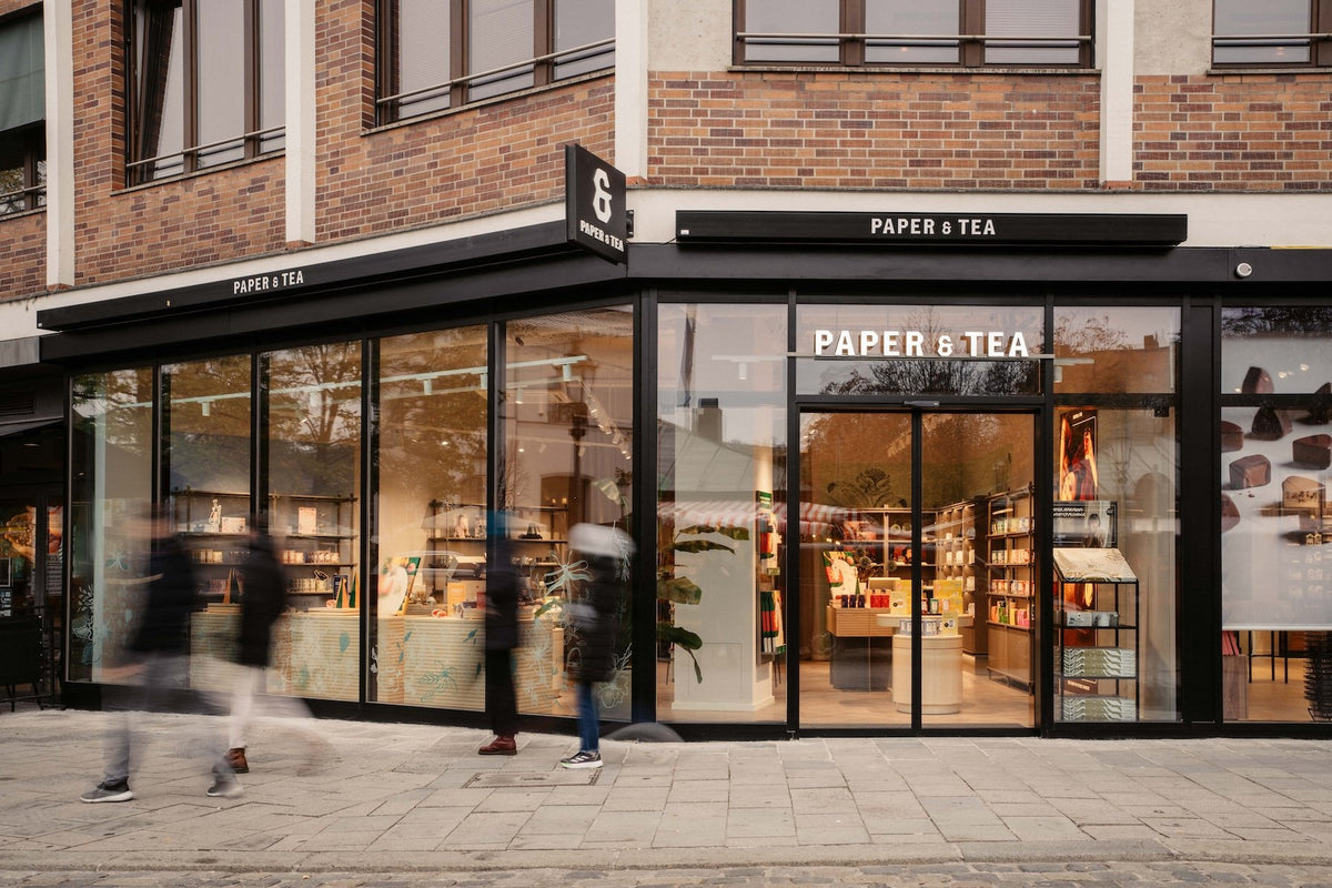 Modernes P&T-Ladengeschäft an einer Straßenecke mit Glasfenstern, Schaufenstern und Fußgängern.